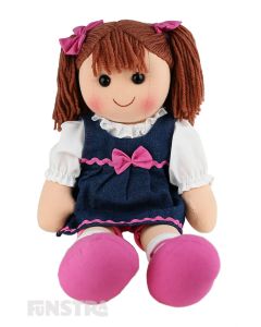 Lacey is a funky doll with a soft cloth body and brown hair tied in pigtails with pink bows and wears a denim dress embellished with pink ribbon and a bow over a white shirt and pink bike shorts.