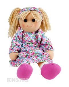 Holly is a fun darling doll with a soft cloth body with blonde hair tied in pigtails secured with a headband and wears a dress featuring a vibrant floral pattern.